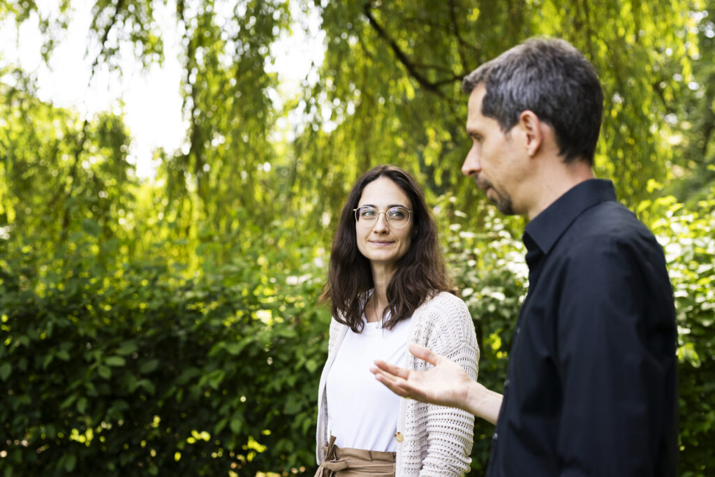 Mann und Frau unterhalten sich, umgeben von Gruenem